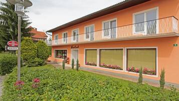 A hotel with a balcony, large windows, and a sign indicating a beer establishment nearby.