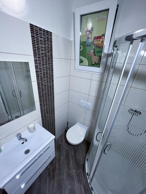 A modern bathroom with a glass shower enclosure, a white sink with a mirror, and a toilet. - Minihotel Vitex (Prague)