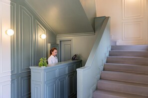 A reception area with a counter, a staircase, and a wall with decorative molding. - Hotel Emi (Calderara di Reno)