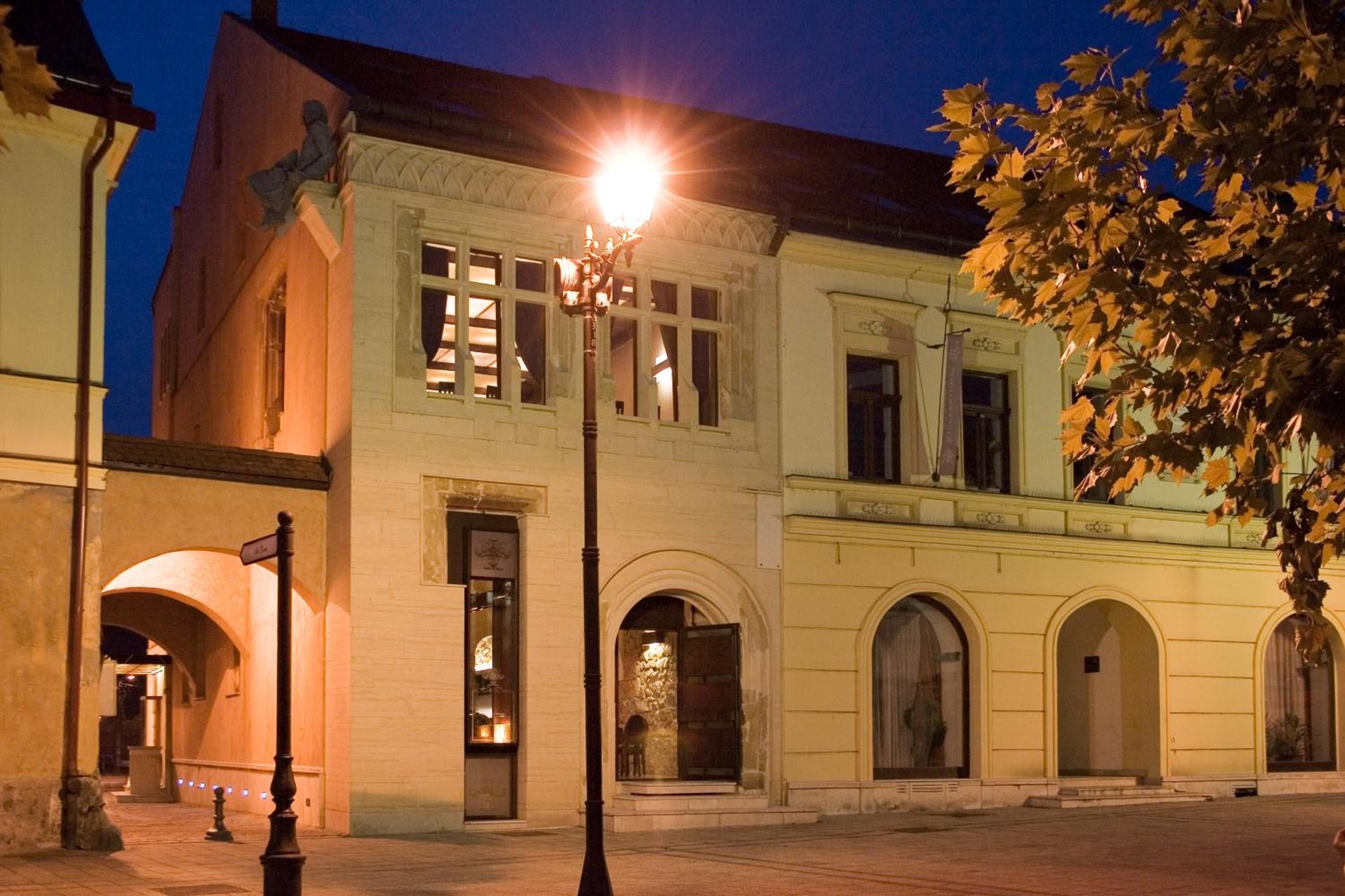 A historic building with arched windows and a street lamp in front.