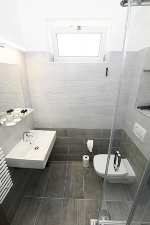 A modern bathroom with a rectangular sink, a toilet, and a shower enclosure.