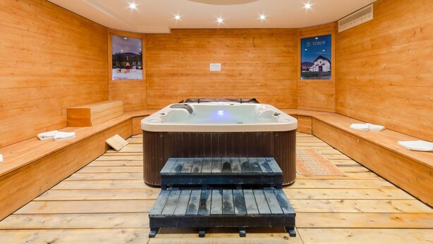 A sauna room with a wooden interior, a hot tub, benches, and a poster on the wall. - Hotel Kelep (Tokaj)