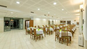 A spacious dining area with multiple tables and chairs, a glass entrance, and a ceiling with a grid pattern. - Hotel Kelep (Tokaj)