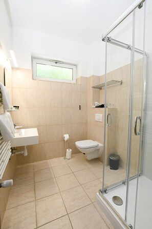 Un baño moderno con cabina de ducha de vidrio, inodoro y lavabo.