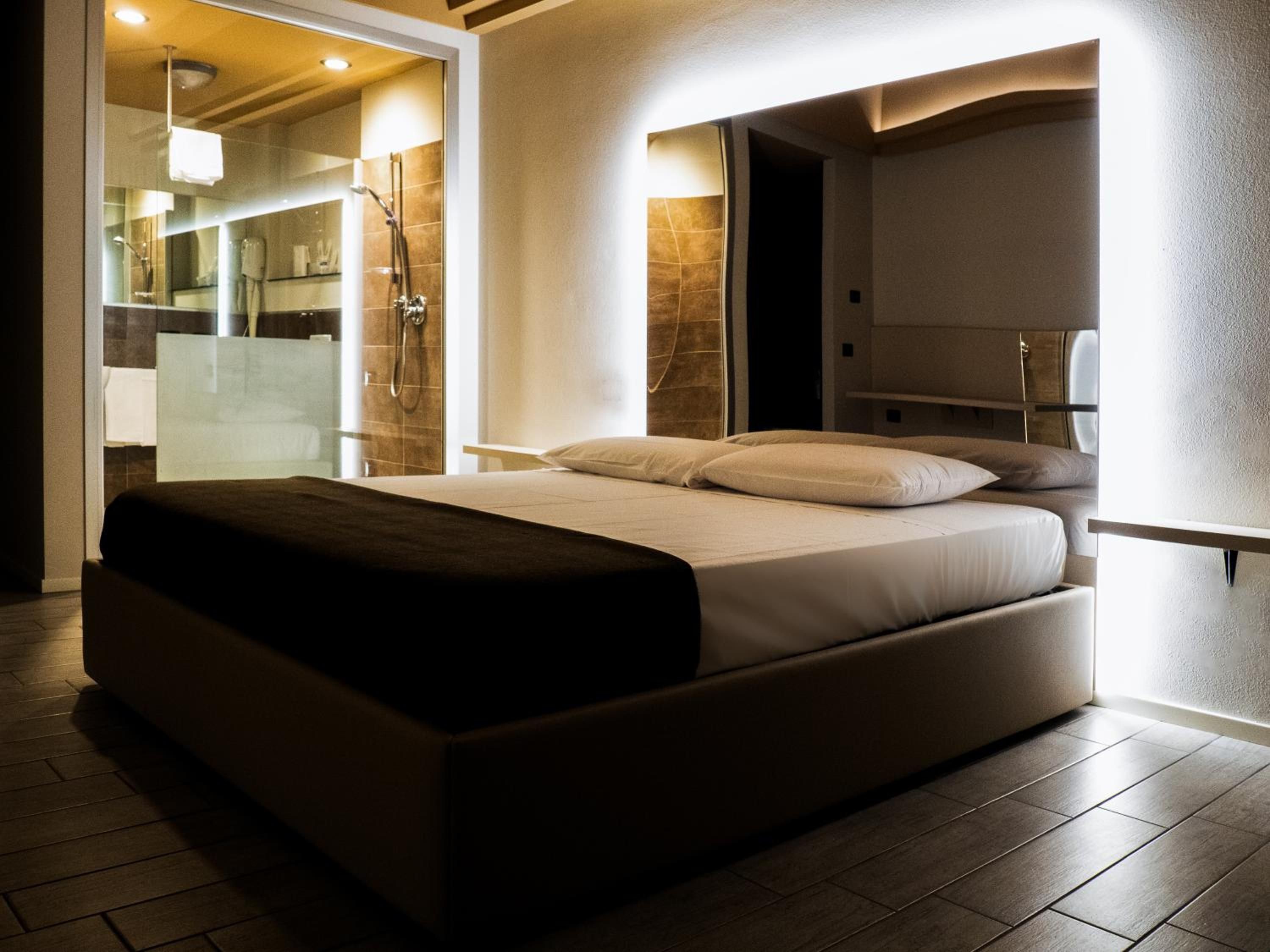 Een moderne slaapkamer met een groot bed, een douchecabine van glas en een zichtbare badkamer.