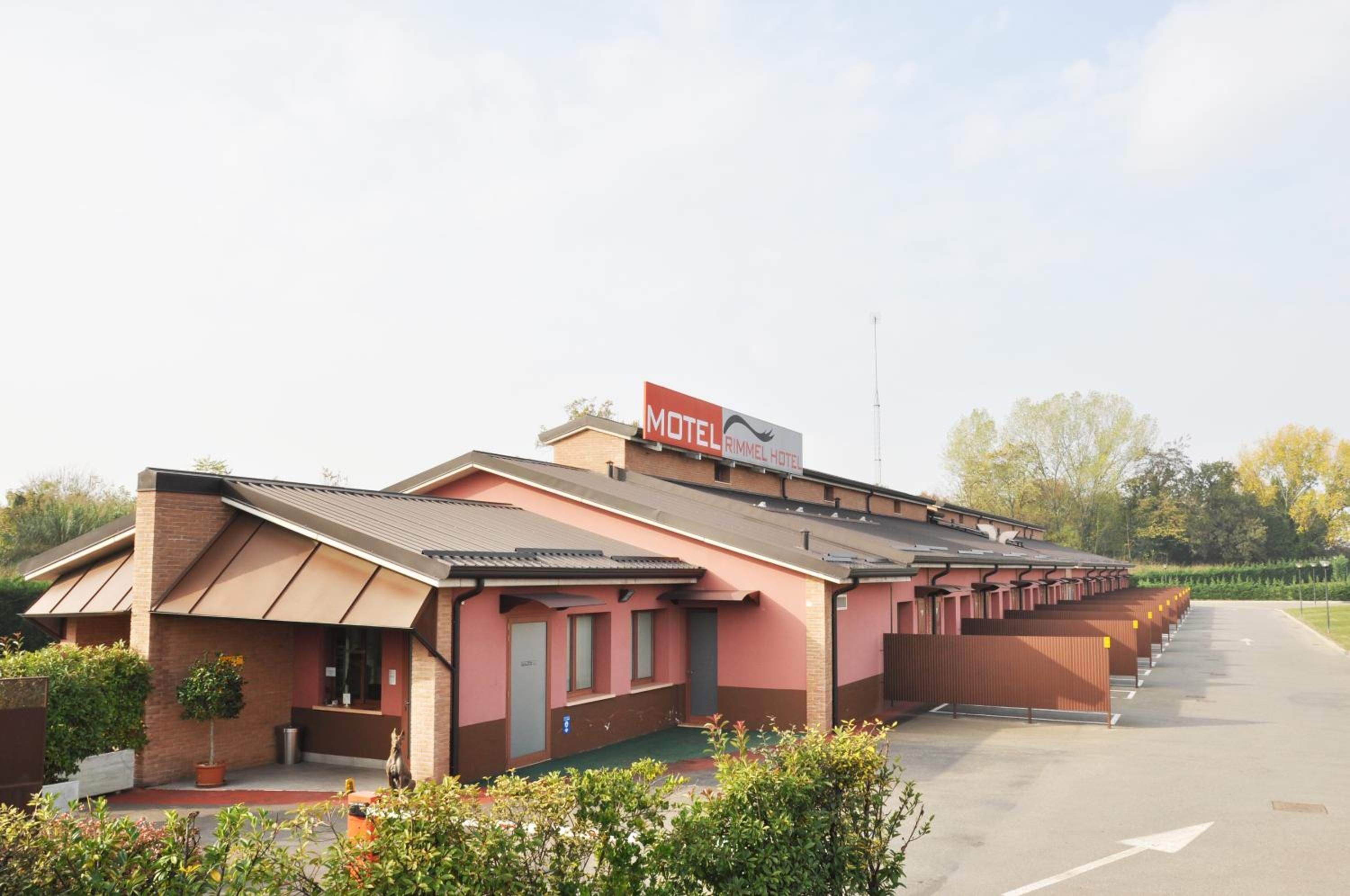 A motel with a red sign, a brick facade, and a parking lot.