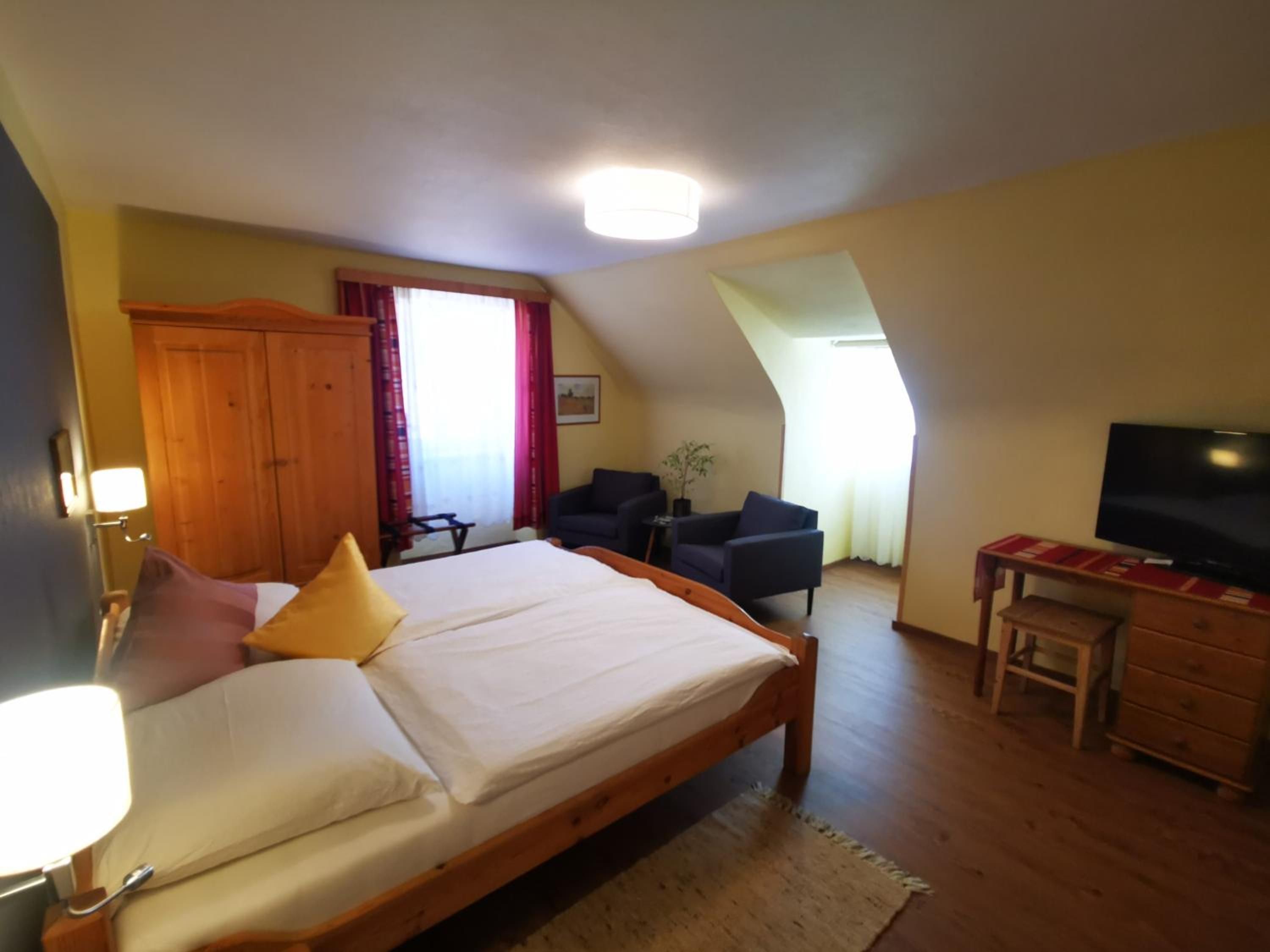 Un dormitorio con cama, escritorio, televisor y silla.
