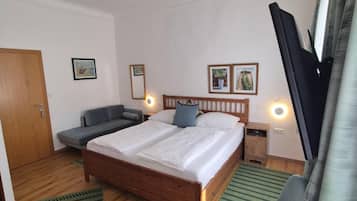 A bedroom with a bed, a chair, a TV, and a door.