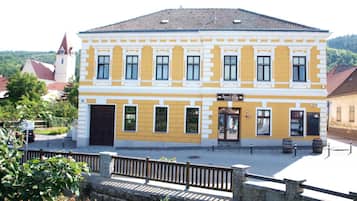 Ein zweistöckiges Gebäude mit einer gelben Fassade, einem zentralen Eingang und einem kleinen Balkon.