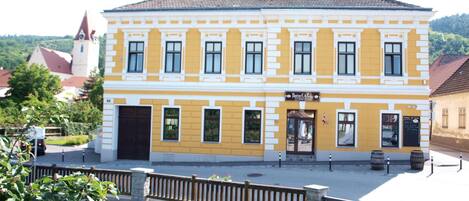 A two-story building with a yellow facade, a central entrance, and a small balcony.