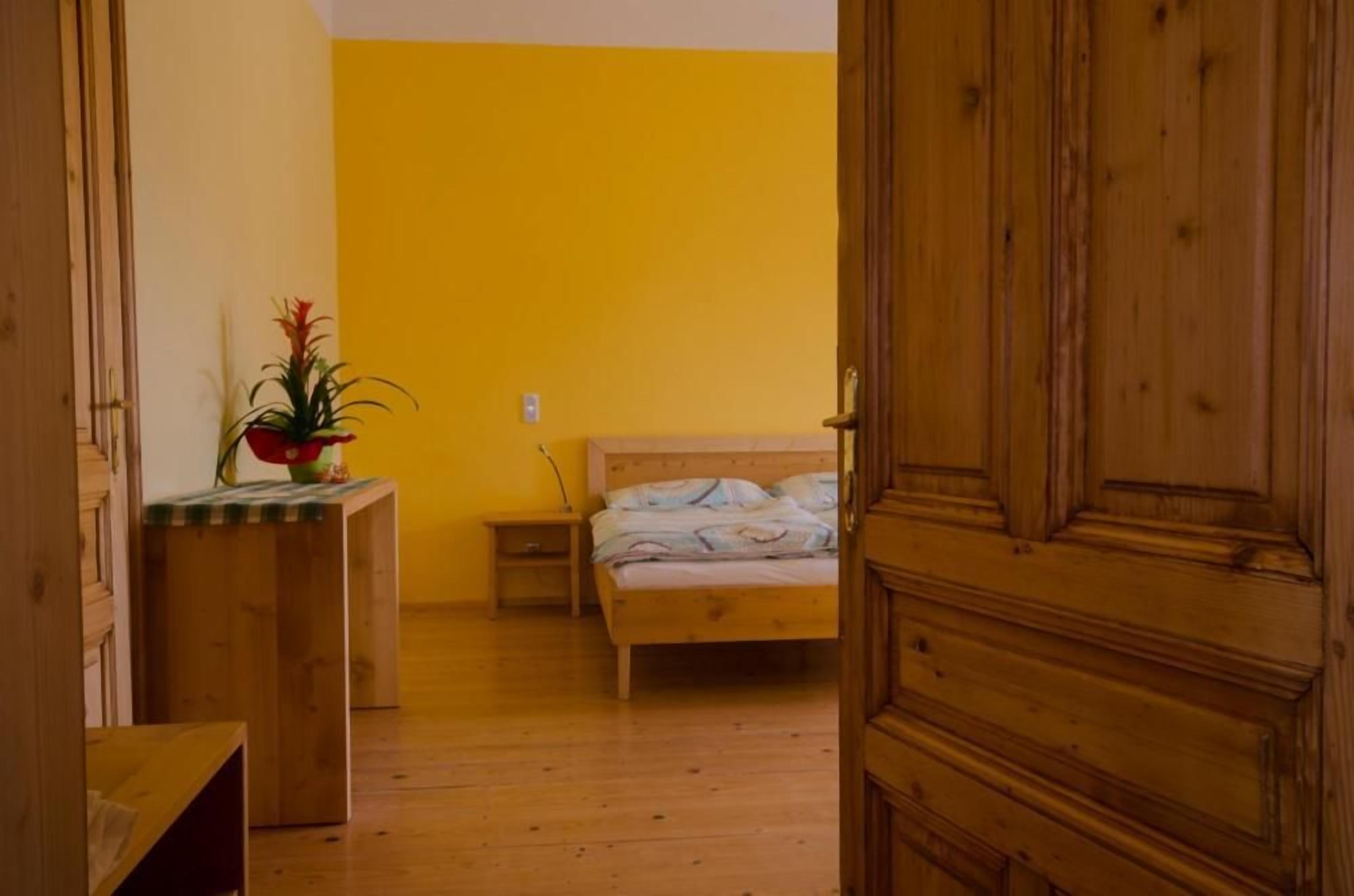 Una habitación con cama, mesita de noche, armario de madera y planta en maceta.