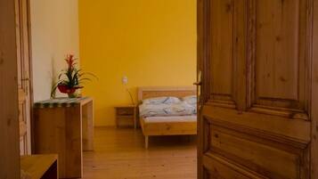Una habitación con cama, mesita de noche, armario de madera y planta en maceta.