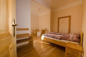 A wooden-framed bed with a plaid blanket, a small wooden table, a chair, and a wooden bench. - Papperl A Pub (Schoenberg am Kamp)