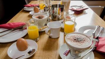 Una mesa de desayuno lista con platos, vasos, una taza y un bol de cereales.
