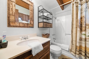 A bathroom with a wooden vanity, a mirror, a shower, and a toilet. - Mama Bear's Cottage (Big Bear Lake)
