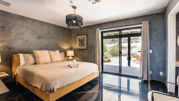 A modern bedroom with a large bed, a bedside table, a lamp, and a view of the outdoors.