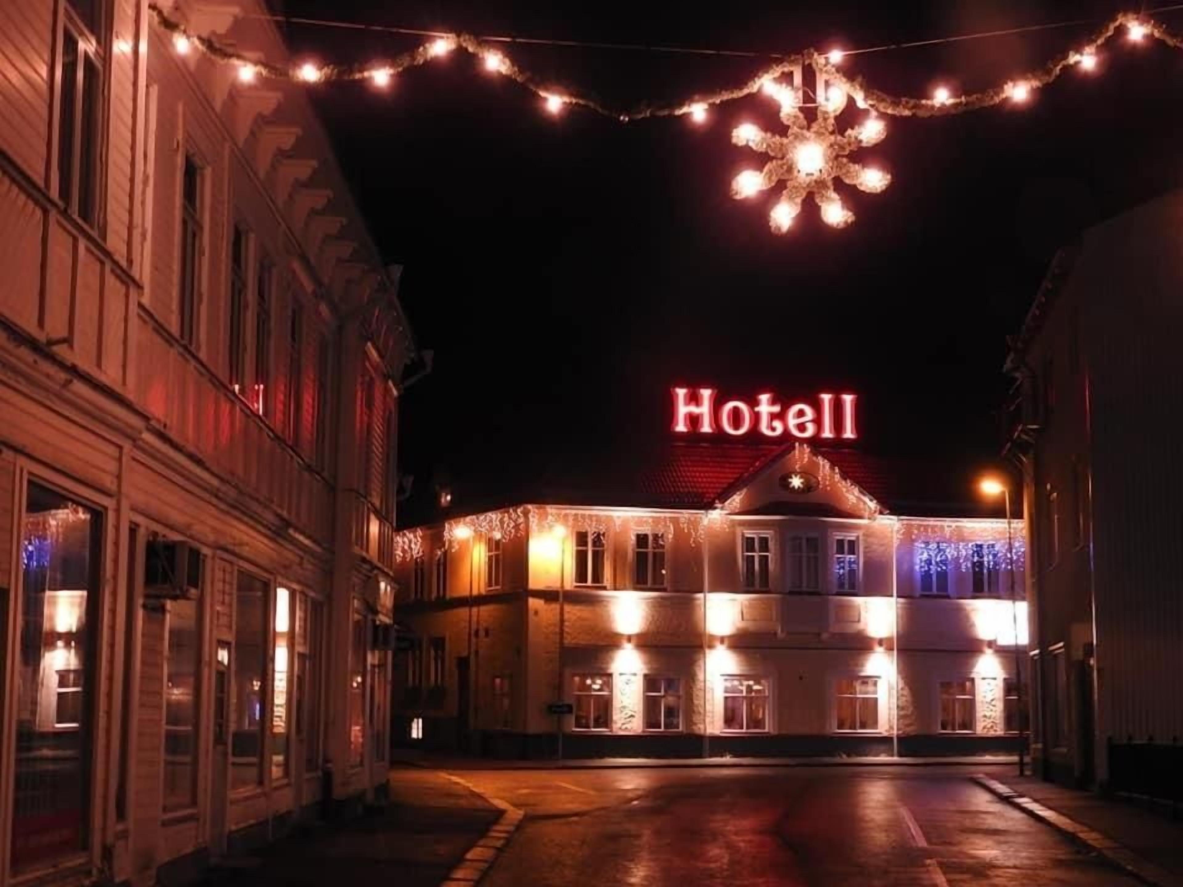 Un hotel con un letrero visible que dice 'Hotel', luces colgantes y una decoración con forma de copo de nieve.