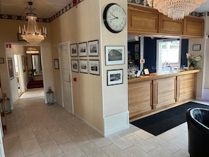 A kitchen with a clock, framed pictures, and a chandelier.