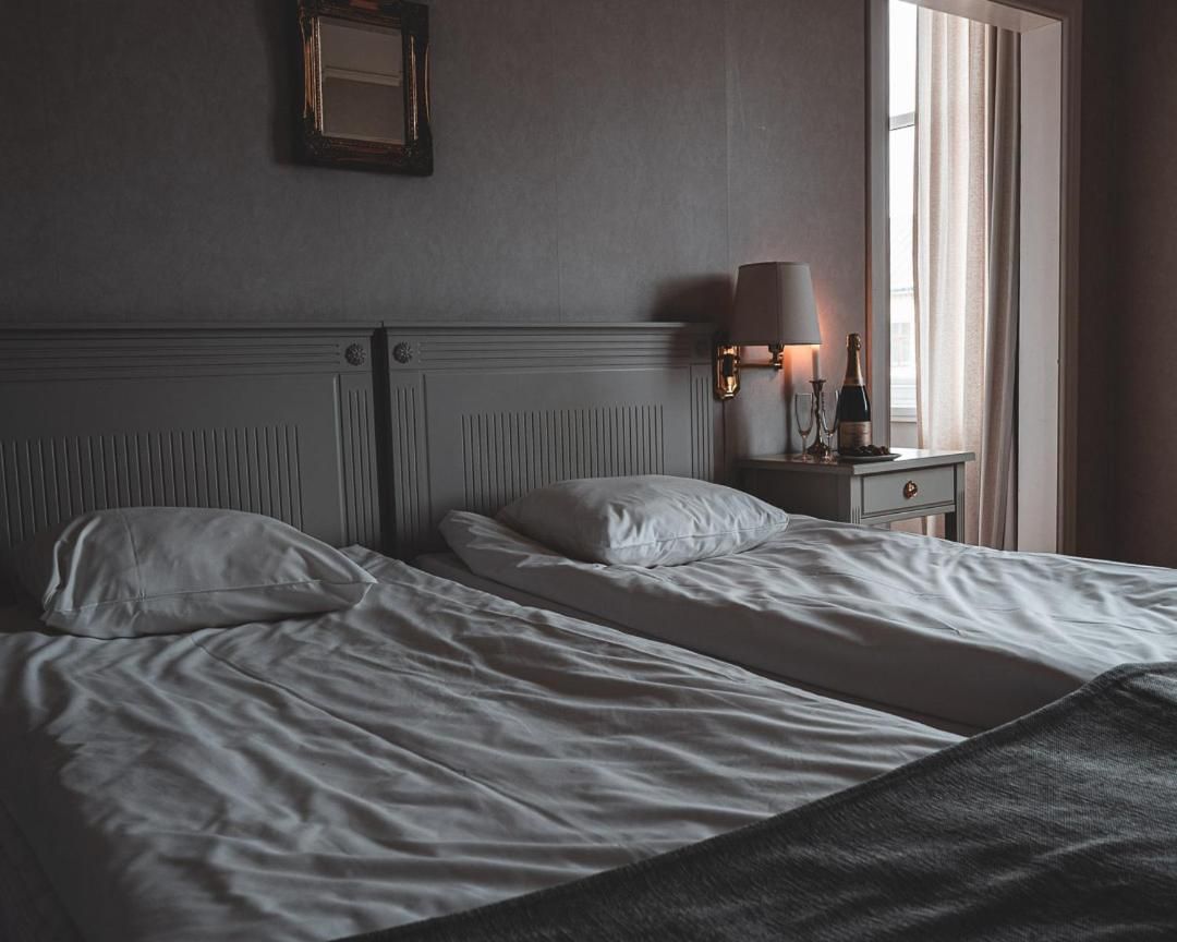 Une chambre d’hôtel avec un grand lit, une table de chevet avec une lampe et une fenêtre avec des rideaux.