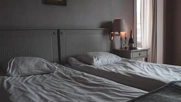 Une chambre d’hôtel avec un grand lit, une table de chevet avec une lampe et une fenêtre avec des rideaux.