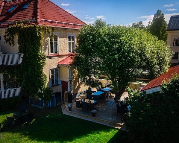 A courtyard with a large tree, outdoor seating, and a building with a red roof.