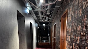 Een gang met een patroon vloerkleed, metalen leidingen aan het plafond en een muur met een rasterpatroon.