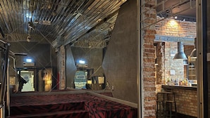 Een trap met een patroonbelegd tapijt dat leidt naar een bar met krukken en een bakstenen muur.