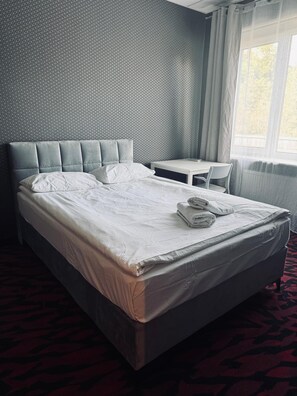 A hotel room with a large bed, a small table, and a chair. - Loft Car Factory (Warsaw)