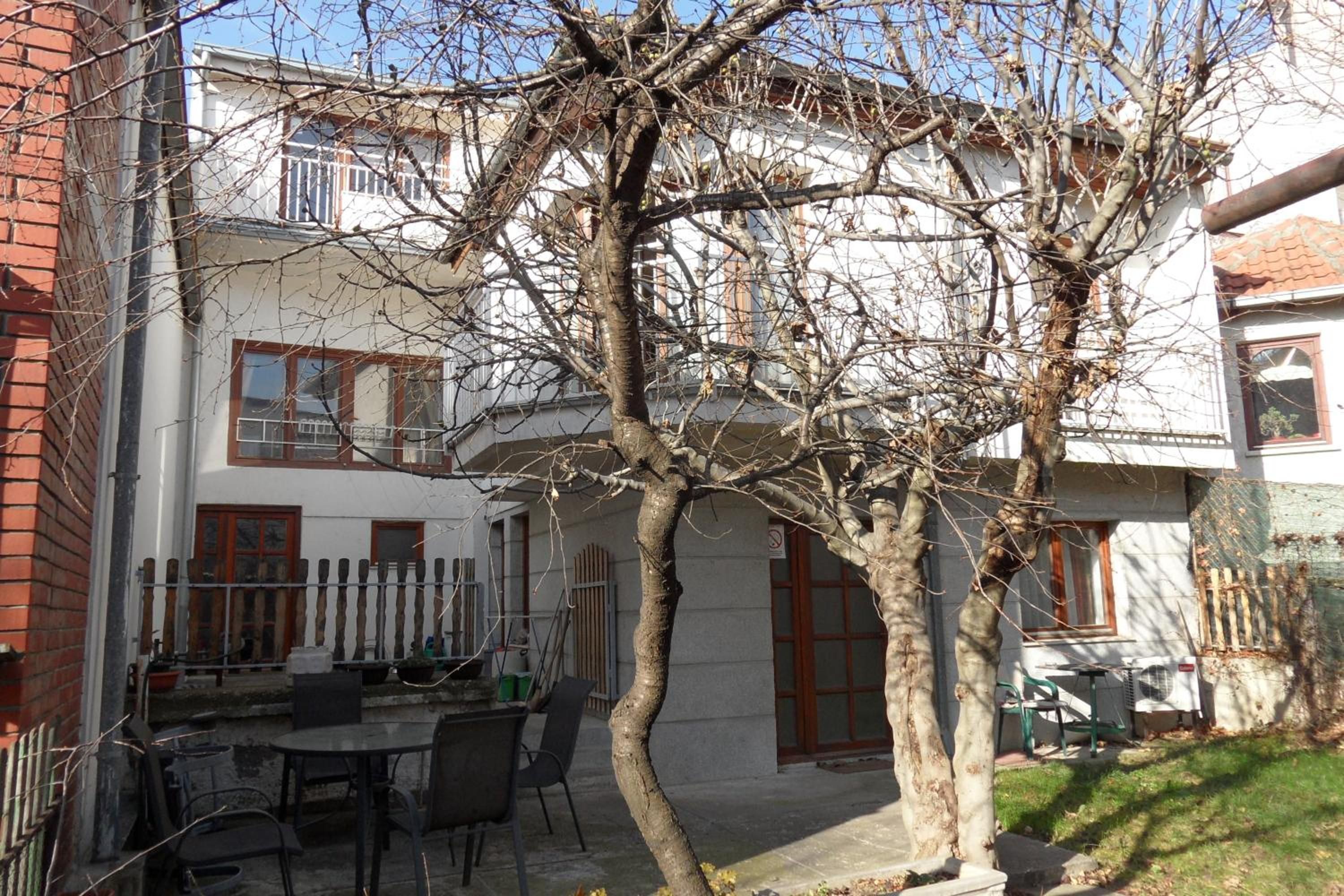 A courtyard with a dining table and chairs, surrounded by buildings with windows and doors.