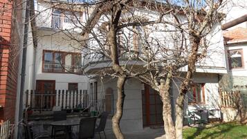 A courtyard with a dining table and chairs, surrounded by buildings with windows and doors.