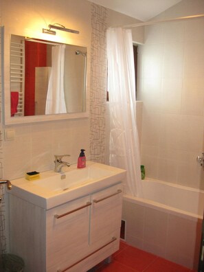 A bathroom with a white sink, mirror, and a bathtub. - Hostel Oasis (Belgrade)