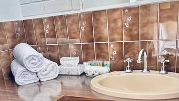 A bathroom with a wooden vanity, a beige sink, and a mirror above it.