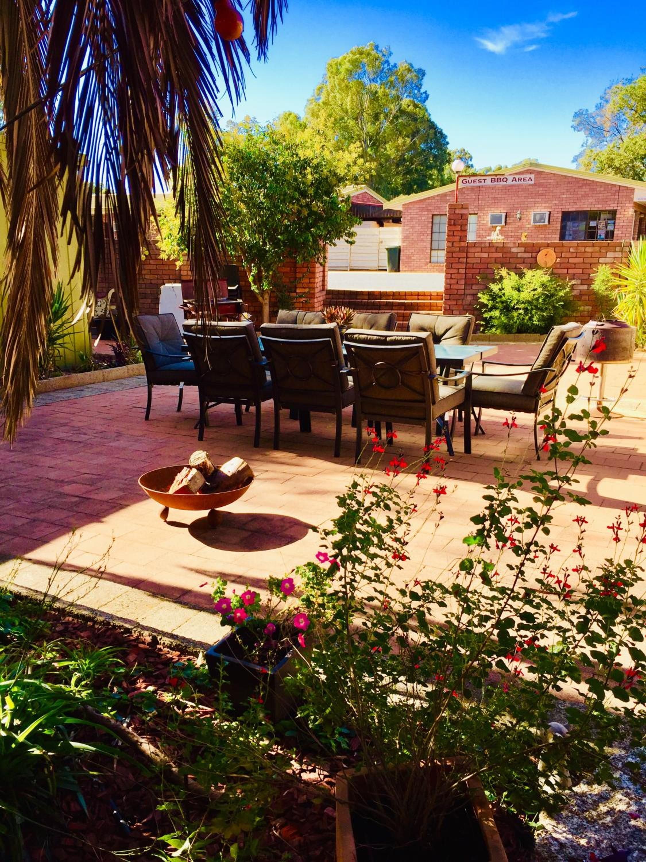 Un patio al aire libre con zona de barbacoa de ladrillo, asientos exteriores y plantas en macetas.