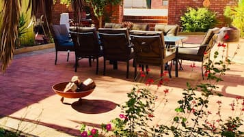 An outdoor patio with a brick barbecue area, outdoor seating, and potted plants.