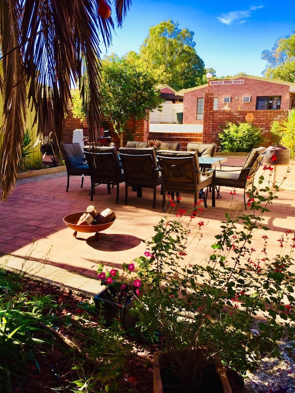 An outdoor patio with a brick barbecue area, outdoor seating, and potted plants.
