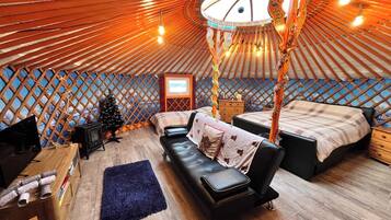 A yurt interior with a bed, sofa, and a small wooden table.