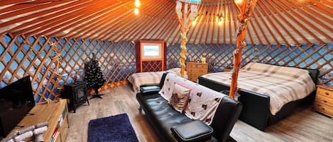 A yurt interior with a bed, sofa, and a small wooden table.