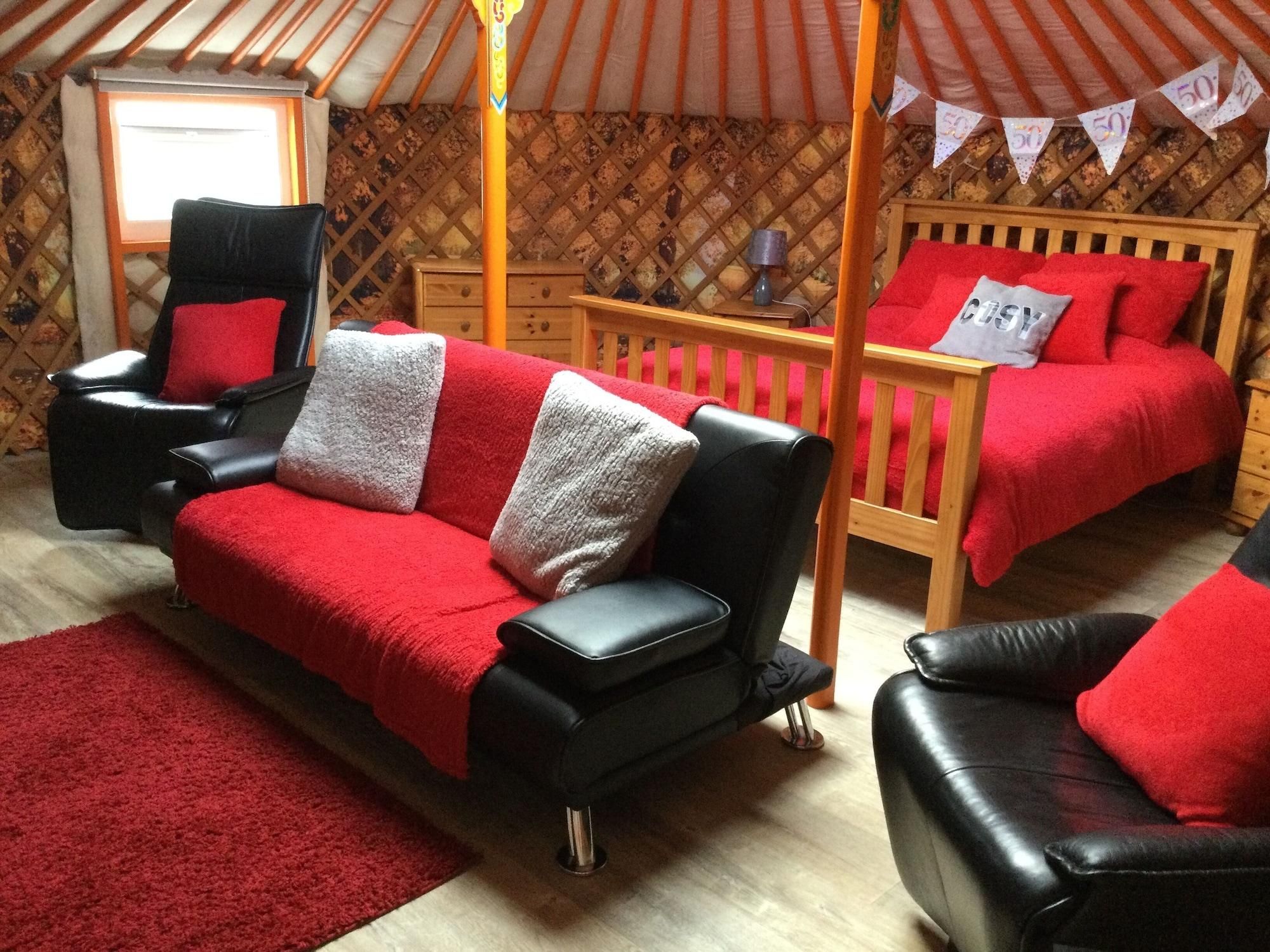 A cozy room with a black leather sofa, a wooden bed, and a red rug.