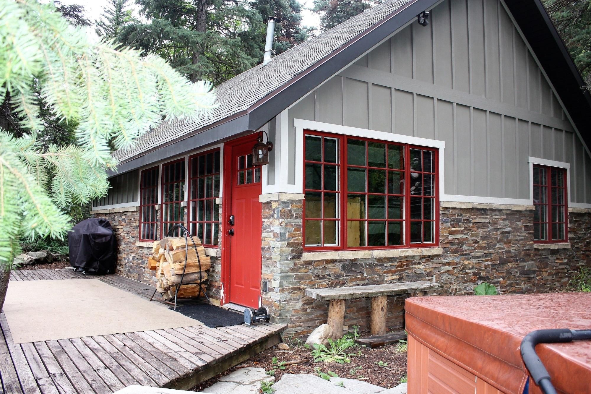 A building with a stone facade, a red door, and large windows with red frames.