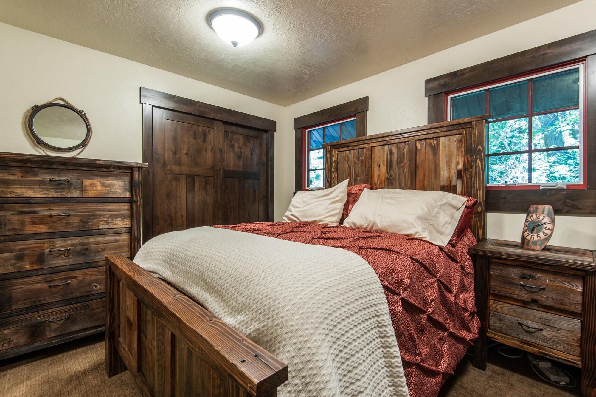 A bedroom with a wooden bed, a dresser, a mirror, and a window with a view.