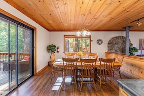 A dining area with a wooden ceiling, a stone wall, and a large window overlooking a forest. - Whiskey Springs By Avantstay Classic Cabin Near (Truckee)