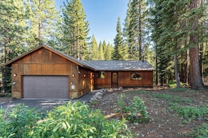 A wooden cabin with a garage, surrounded by a forest. - Whiskey Springs By Avantstay Classic Cabin Near (Truckee)