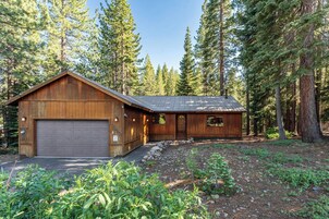 A wooden cabin with a garage, surrounded by a forest.