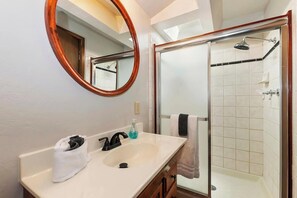 A bathroom with a sink, mirror, and shower. - Summit Happy Mountain Cabin (Big Bear Lake)