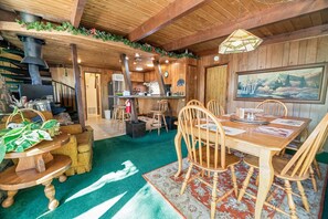 A cozy wooden interior with a dining area, kitchen, and a fireplace. - A Ski View (Big Bear Lake)
