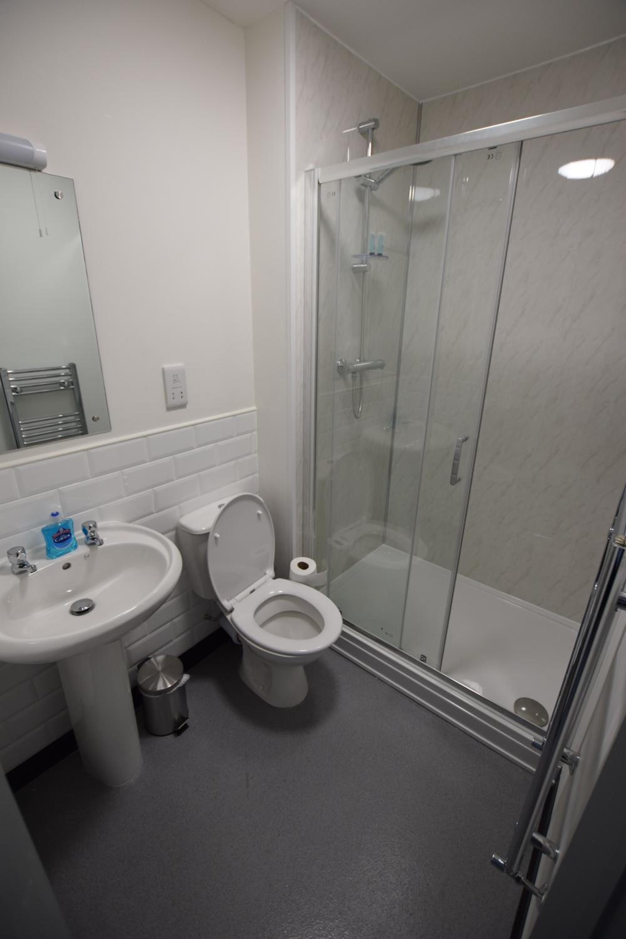 A bathroom with a sink, toilet, and glass-enclosed shower stall.