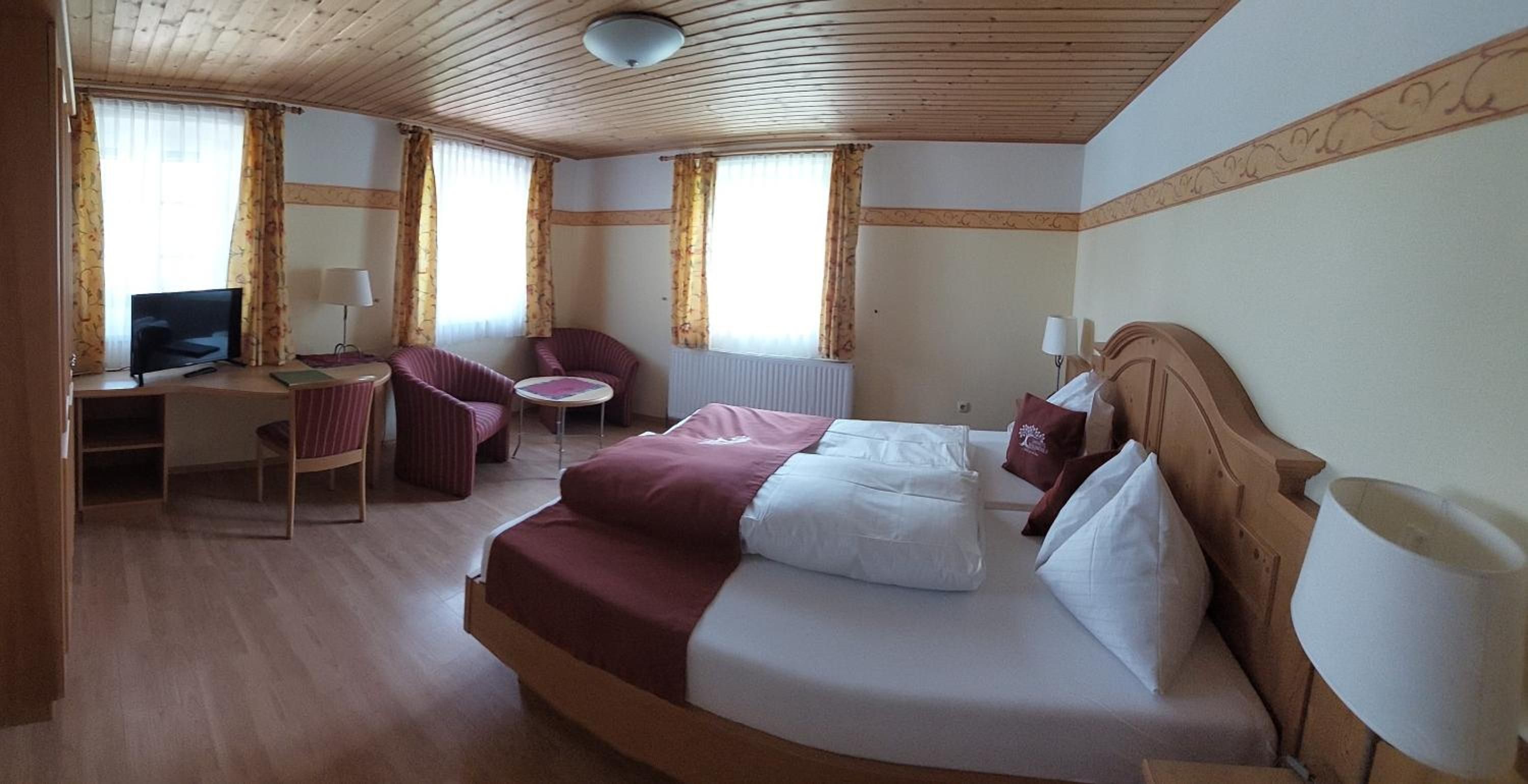 Ein Hotelzimmer mit einem Bett, einem Schreibtisch mit Computer, einem Stuhl und einem kleinen Tisch.