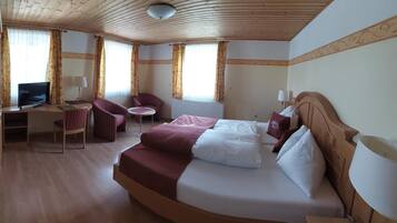 Ein Hotelzimmer mit einem Bett, einem Schreibtisch mit Computer, einem Stuhl und einem kleinen Tisch.
