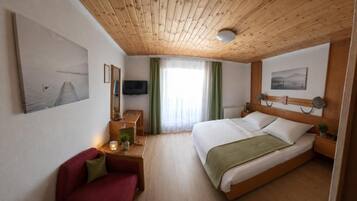 Ein Hotelzimmer mit Bett, Schreibtisch, Stuhl, Fernseher und Bildern an den Wänden.
