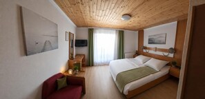A hotel room with a bed, a desk, a chair, a television, and artwork on the walls. - Landhotel Waldmv Hle (Straß im Attergau)